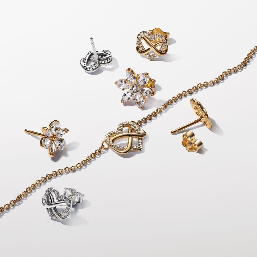 Glittrande stiftörhängen med en evighetssymbol