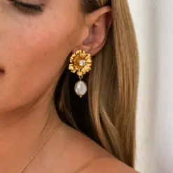 Låt oss presentera våra lyxiga Blossom Pearl Earrings! Med en vacker blomdesign dekorerad med gnistrande kristaller, avslutas varje örhänge med en skimrande pärldroppe som rör sig elegant vid varje steg. Dessa örhängen ger en klassisk men cool touch och passar perfekt för både dagtidens elegans och kvällens glamour. Storlek: 4,5 x 2,4 cm Plätering: 18K Guld / Rhodium Världens högsta kvalité på kristaller Graverad logotyp Designad i Sverige, handgjord i Grekland