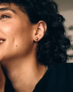 Detaljbild av små örhängen i guld med studs-design