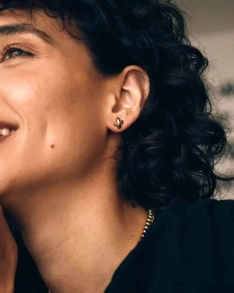 Detaljbild av små örhängen i guld med studs-design