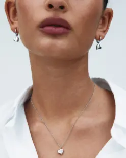 Detaljbild av rostfria hoop-örhängen med hjärtdesign