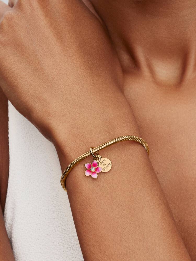 Pandora Disney Vaiana-blomma hängberlock på modell med Moments-armband i guld – Disney x Pandora